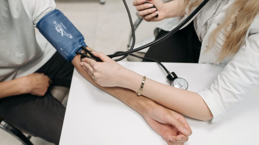 medical professional taking someone's blood pressure with blood pressure sleeve
